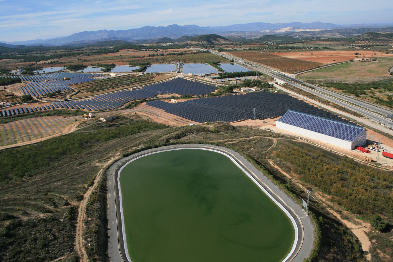 Vista aérea de la planta fotovoltaica de Ecoparque Solar de Bullas con la balsa y la nave de servicio